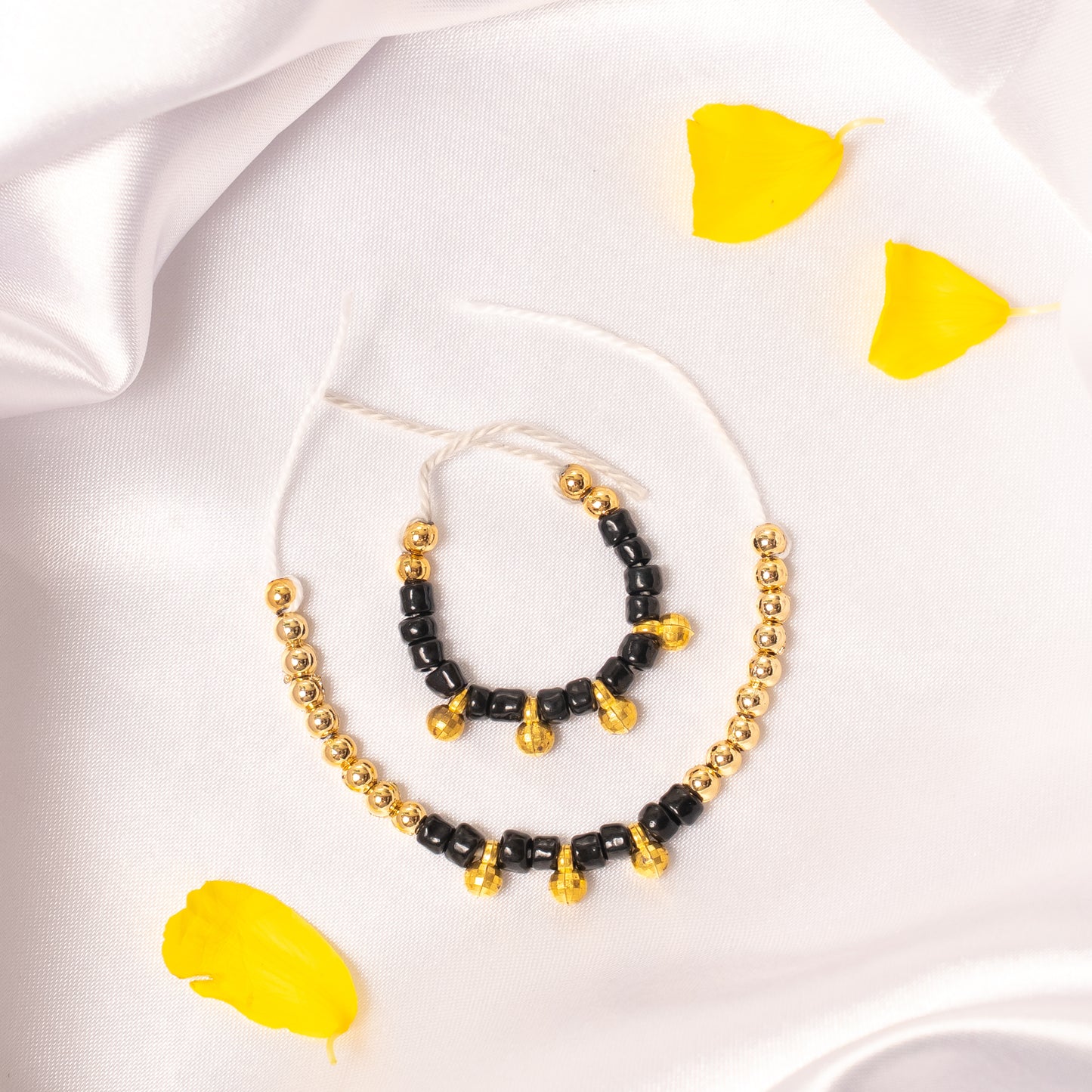 Necklace with black and gold beads on a white fabric background 
